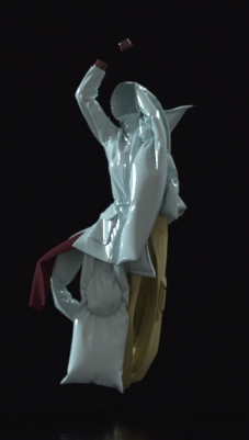 cloth variation: a humanoid figure comprised of a plastic-like 
	sari and canvas pants wrapped around an absent body; it stands on one leg, knee bent, with arms raised above its hooded head